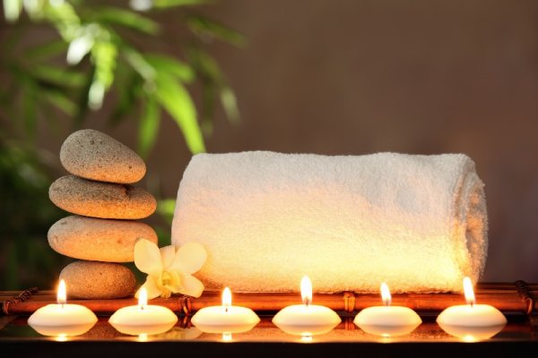 Six little candles in fornt of a white towel and four rocks placed one on another