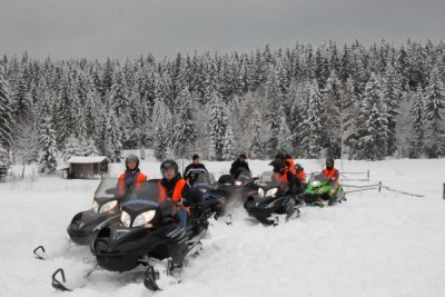 Dziesięć osób siedzących na skuterach śnieżnych, zimą w okolicy hotelu Złoty Groń